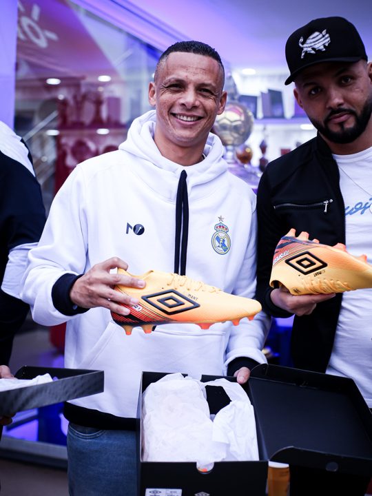 Participantes apresentam chuteiras douradas com o duplo diamante Umbro visível. Registro do Churrasco Fair Play, no acervo da SCP 2026.