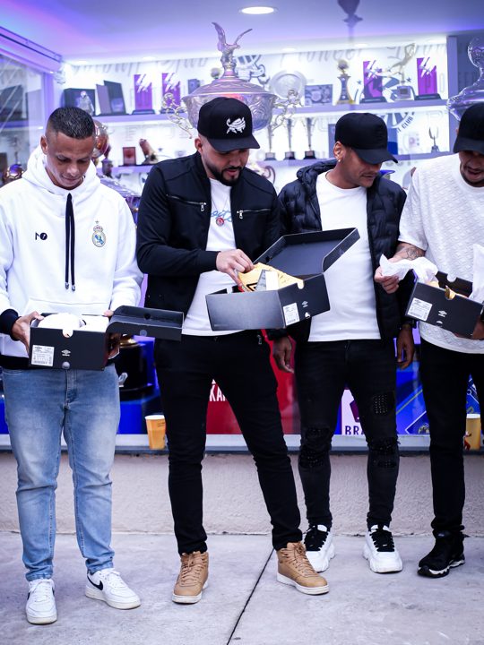 Participantes retiram os produtos de caixas Umbro, com a identificação da marca visível nas embalagens. Registro do Churrasco Fair Play, no acervo da SCP 2026.