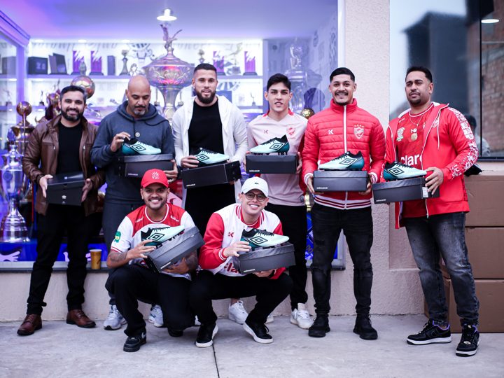Participantes posam com chuteiras verdes e embalagens Umbro em registro coletivo do Churrasco Fair Play.