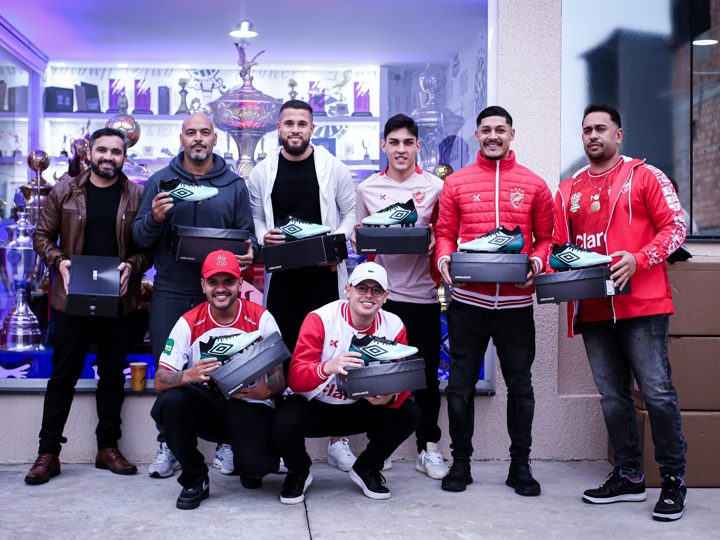 Outro registro coletivo com participantes, chuteiras verdes Umbro e suas embalagens durante o encontro.