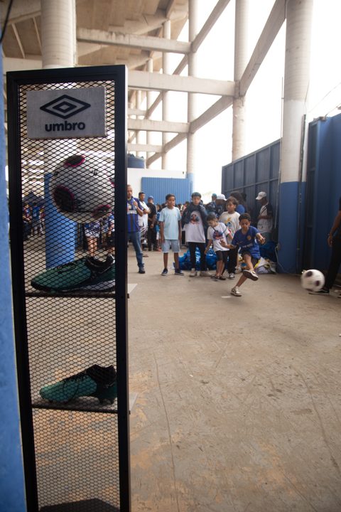 Expositor com a marca Umbro, bola e chuteiras em primeiro plano, enquanto o público participa de uma atividade com bola no espaço da Grande Final da SCP 2026.