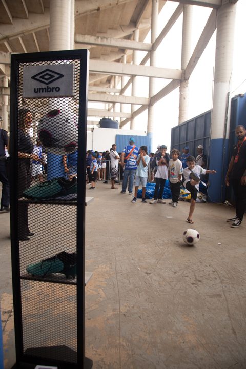 Expositor com a marca Umbro, bola e chuteiras em primeiro plano, enquanto o público participa de uma atividade com bola no espaço da Grande Final da SCP 2026.