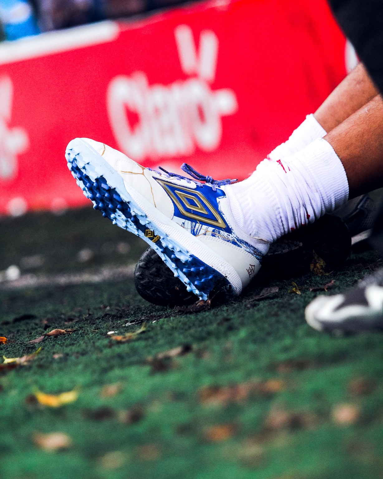 Detalhe de chuteira Umbro em uso à beira do campo. A identificação de primeira fase acompanha o arquivo recebido; o registro não determina a origem do fornecimento nem a exclusividade contratual.