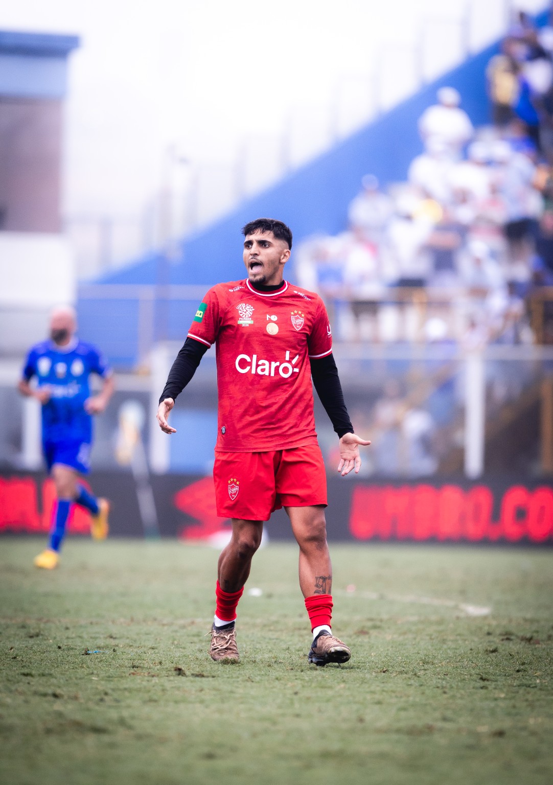 Atleta em campo com a marca Umbro no painel de LED ao fundo. O original VERO-205.jpg integra a pasta Grande Final / Thiago da SCP 2026. A fotografia não mede duração ou frequência das inserções.