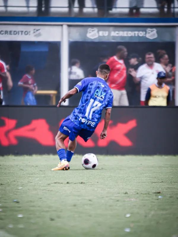 Jogador com a camisa azul número 17 aparece junto à bola, com o duplo diamante visível na bola e nas chuteiras douradas.