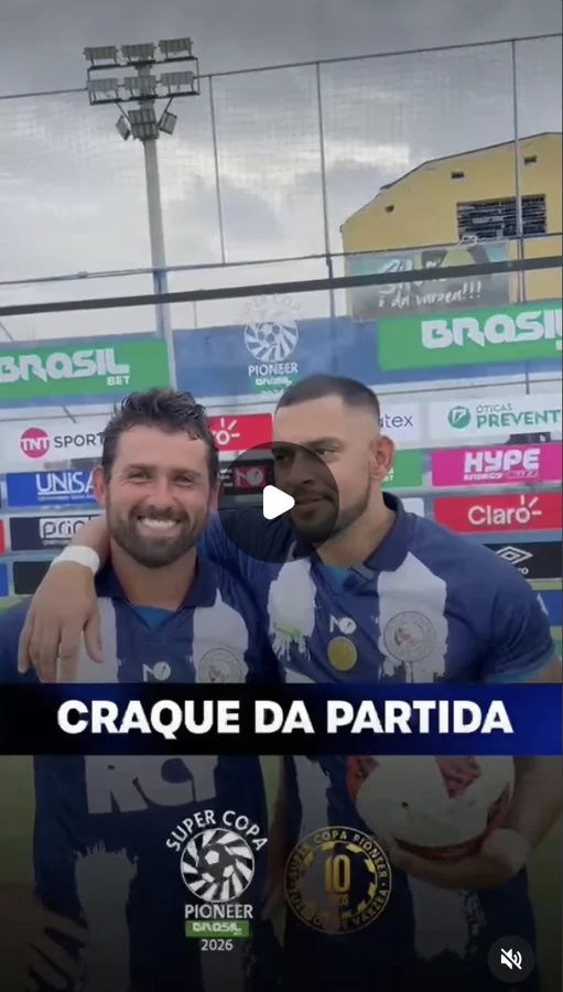Captura de vídeo com dois participantes de uniformes azuis diante do painel de patrocinadores. Um deles segura uma bola; a marca Umbro aparece no painel e a tela exibe “Craque da partida”. Registro enviado pela Scout Sports para o acervo do Hat-trick Umbro.