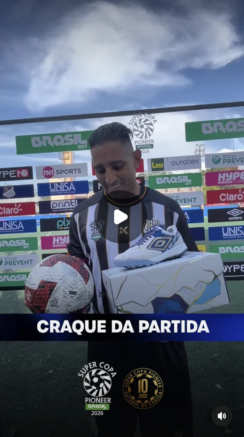 Captura de vídeo de participante com uniforme listrado, uma bola e uma caixa com calçado Umbro. O duplo diamante está visível no produto e no painel ao fundo; a tela exibe “Craque da partida”. Registro enviado pela Scout Sports para o acervo do Hat-trick Umbro.