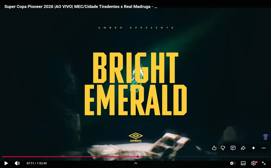 Tela do comercial “Bright Emerald”, com “Umbro apresenta” e o logotipo da marca. O título visível identifica MEC/Cidade Tiradentes × Real Madruga, e o player marca 57:11. Captura fornecida como exemplo de comercial no intervalo.