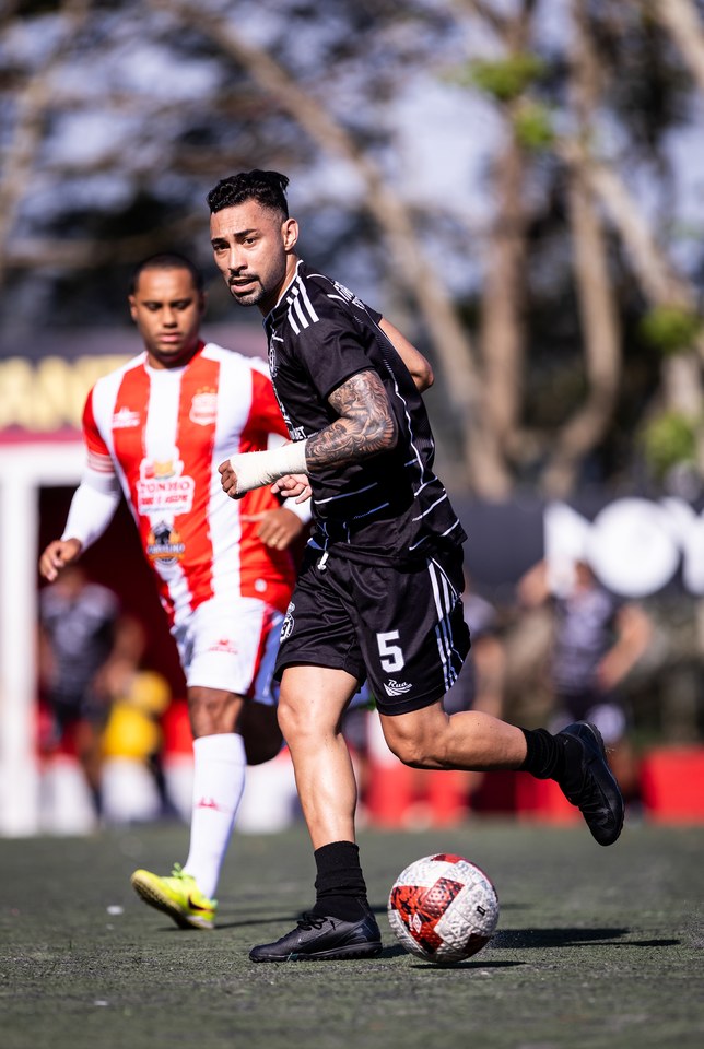 Segundo enquadramento de atleta do T9 com a bola Umbro em jogo, com adversário ao fundo. Origem: oitavas de final em Santa Amélia, acervo SCP 2026. A exclusividade e o quantitativo de bolas fornecidas não são determinados pela fotografia.