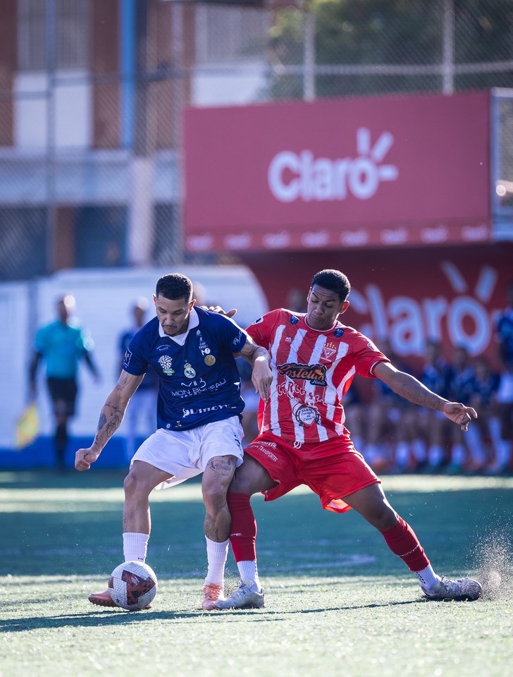 Disputa de bola entre atletas de Real Madruga e Guaraciaba, com o duplo diamante Umbro visível na bola. Fotografia localizada na pasta desse confronto nas quartas de final da SCP 2026. O registro documenta o uso no lance fotografado.